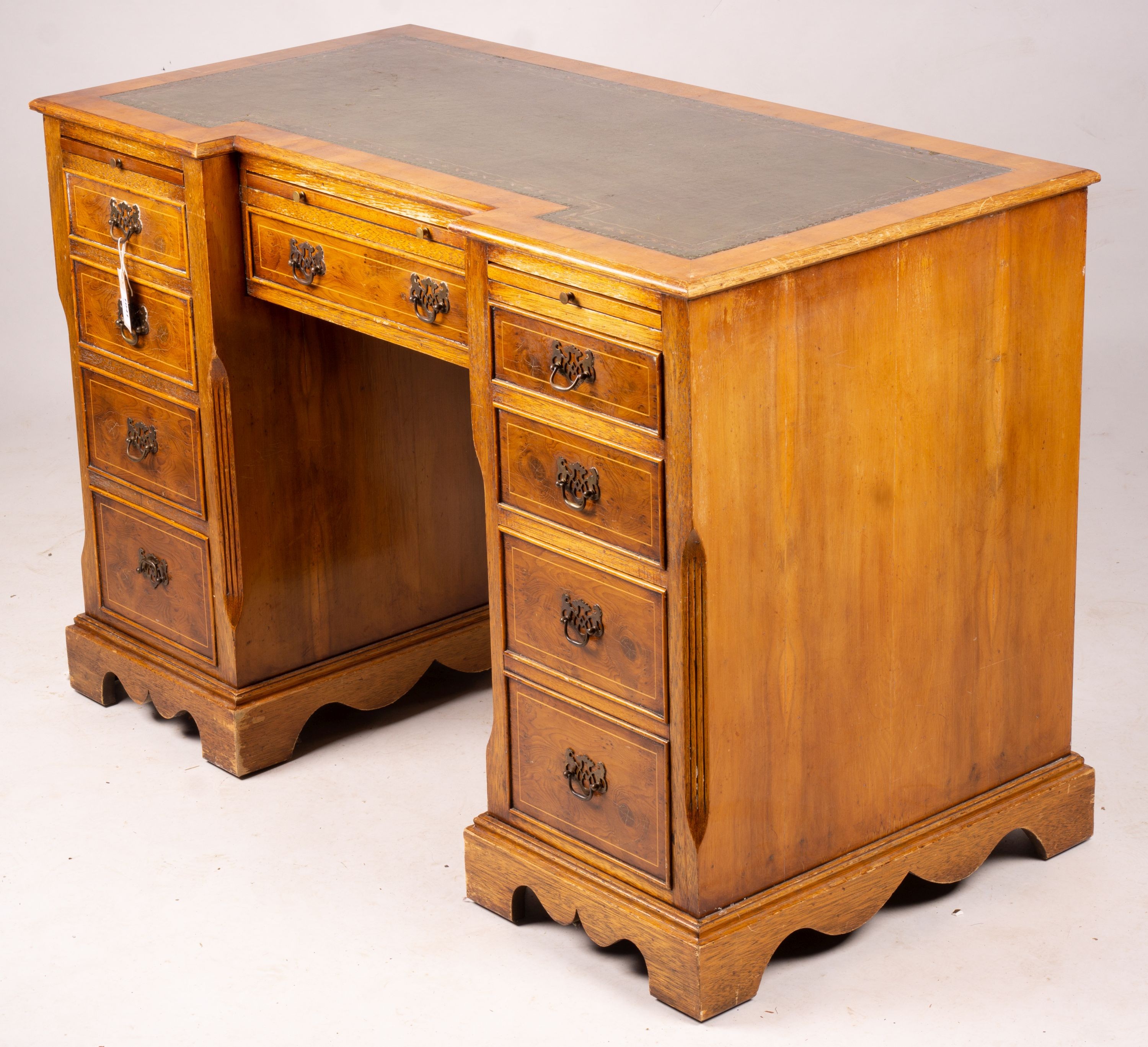 A reproduction yew inverse breakfront kneehole pedestal desk fitted green skiver, width 114cm, depth 58cm, height 77cm